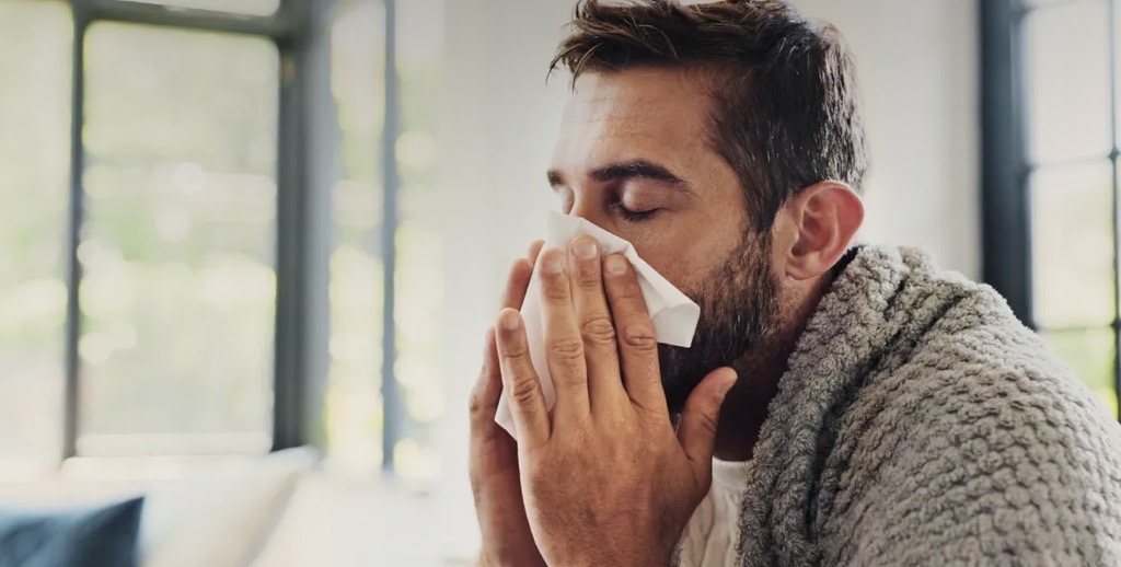 Veteran with chronic rhinitis congestion blowing his nose at home.